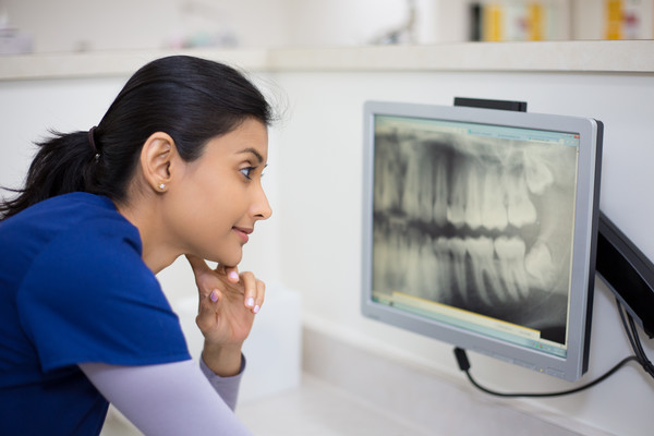 assistant looking at radiograph on screen