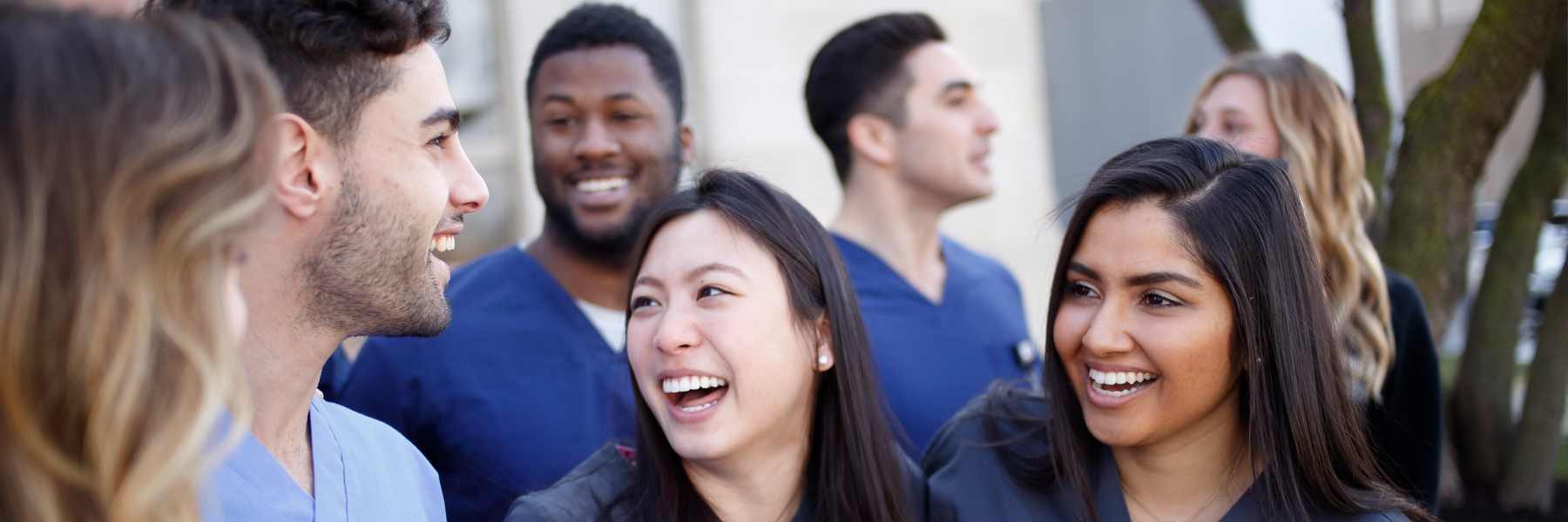 Dentistry students wear scrubs and smile at each other. 