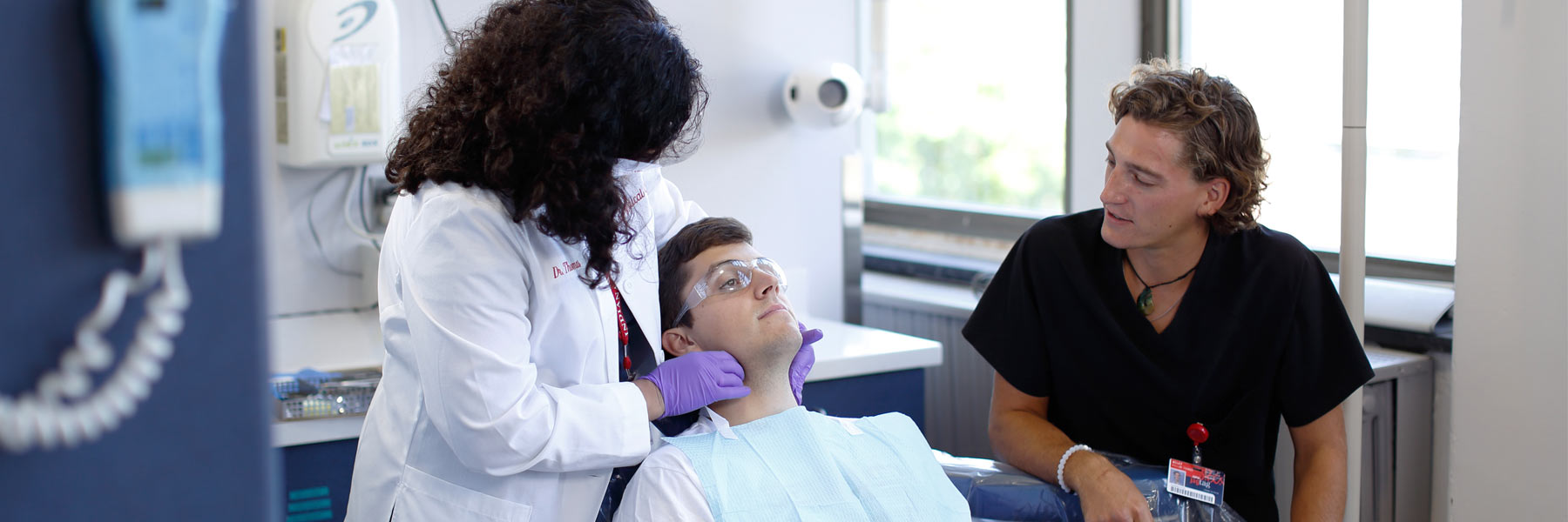 A dentistry student observes as a dentistry professional works with a patient. 