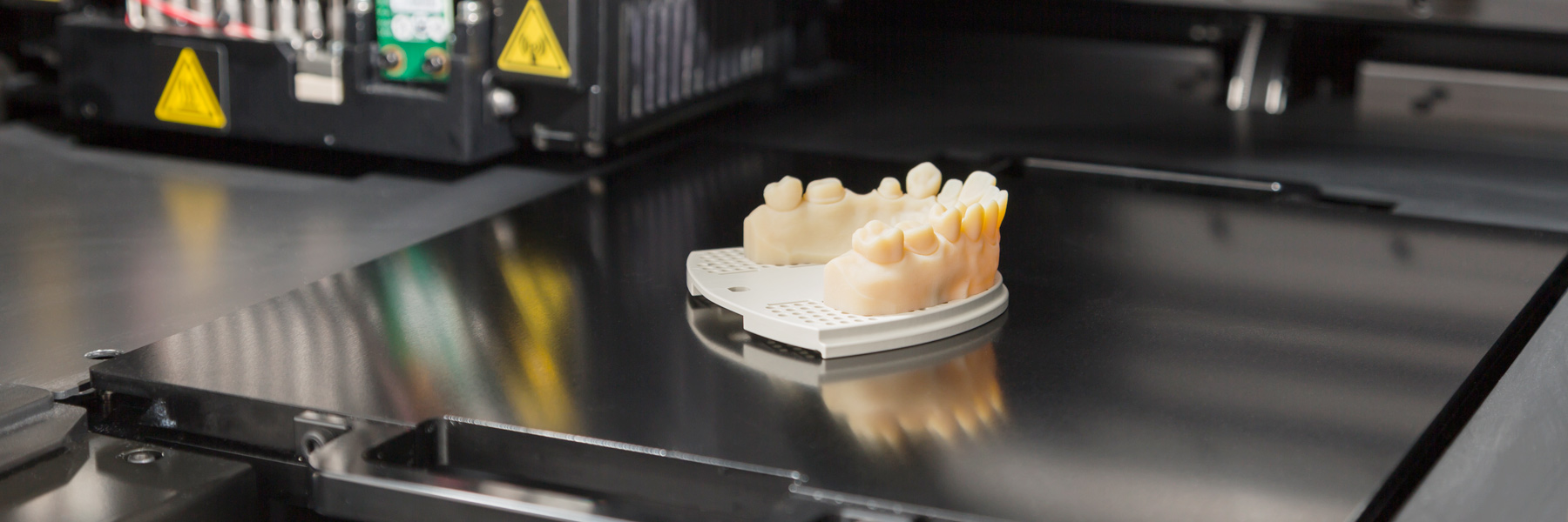 A close-up of a silicone teeth mold sitting on a metal platform