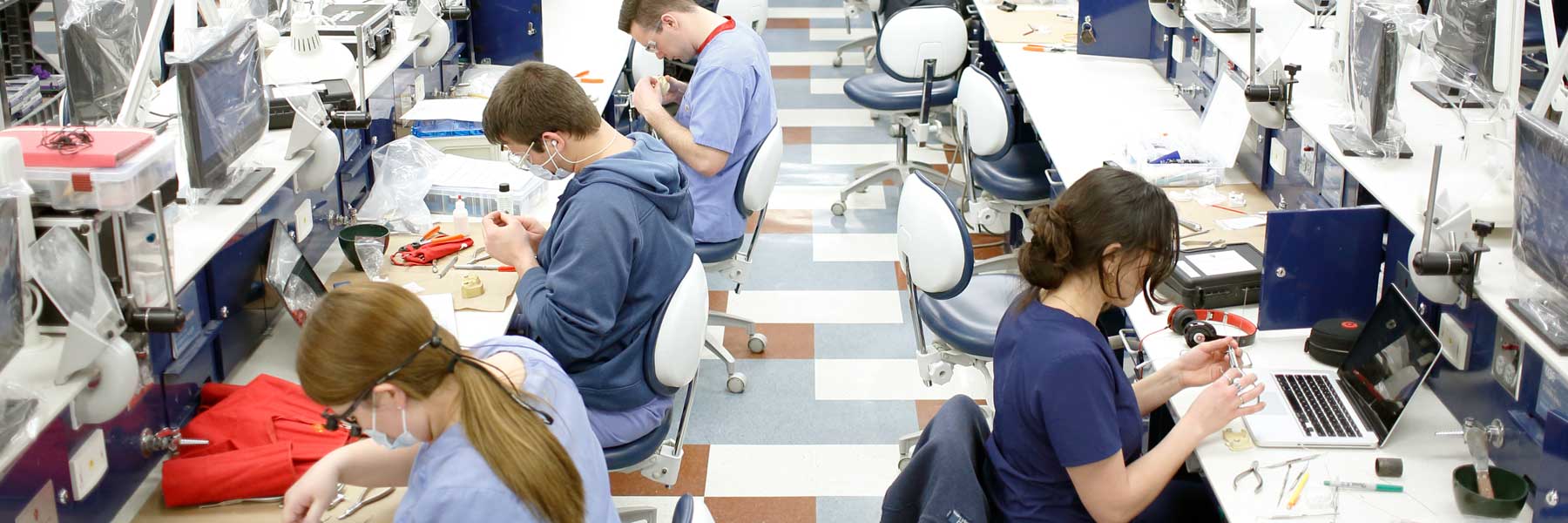 Dentistry students practice using dental tools at research lab stations.